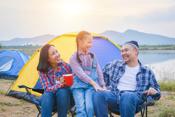 Wall Mural - Group of asian family travel and camping at lakeside in forest ,sitting all together and smile. Family and outdoor activity concept.