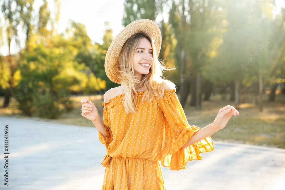 Beautiful young woman in stylish yellow dress and straw hat outdoors ...
