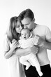 © shunevich - Black and white photo of a young caring family with a small child in their arms. The parent gently kisses the baby, photographed as a keepsake, enjoying the moment. Family concept.