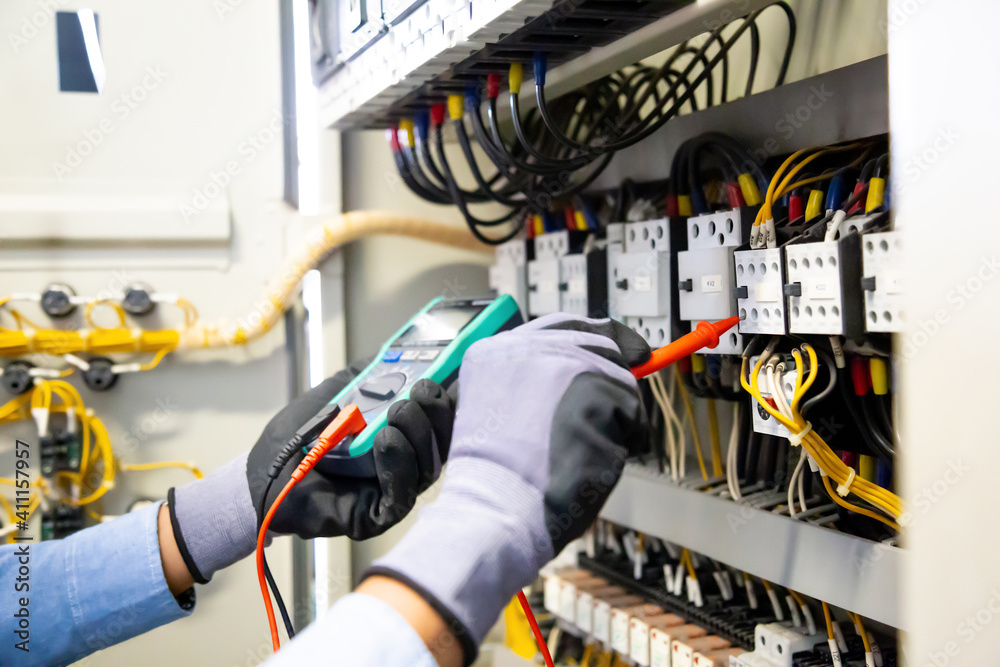 Electrical engineer using digital multi-meter measuring equipment to ...