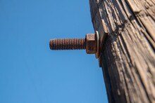 Old Rusty Screw And Bolt On A Wooden Pole With Blue Sky