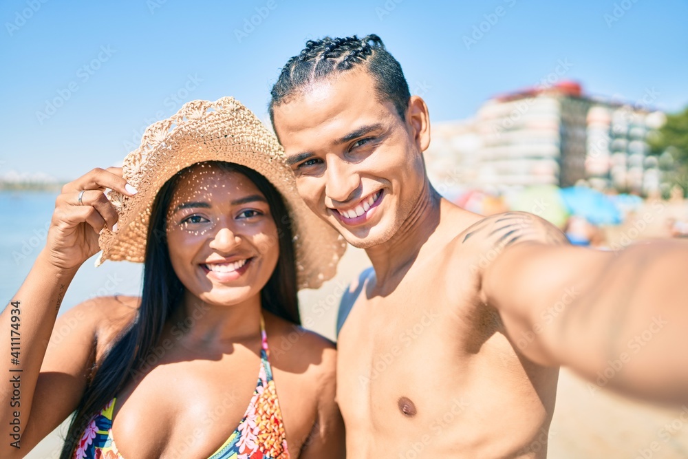 Young latin couple smiling happy making selfie by the camera at the beach.