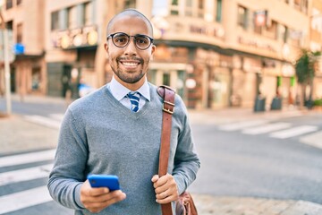 Poster - Young african american businessman smiling happy using smartphone at the city.