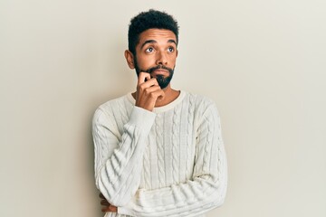 Wall Mural - Handsome hispanic man with beard wearing casual winter sweater thinking concentrated about doubt with finger on chin and looking up wondering