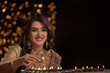 woman in  saree lighting diya	