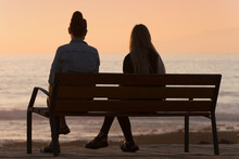 Silhouette Of Two Women On A Bench By The Sea