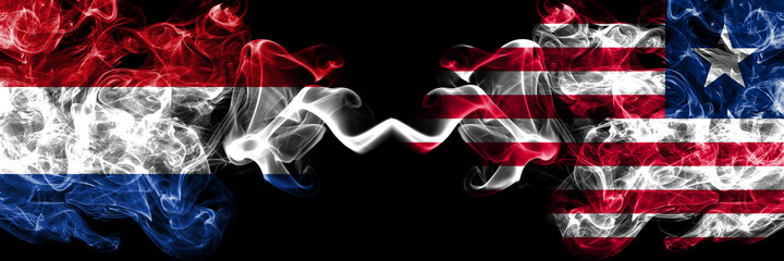 Netherlands vs Liberia smoky mystic flags placed side by side. Thick colored silky abstract smoke flags.