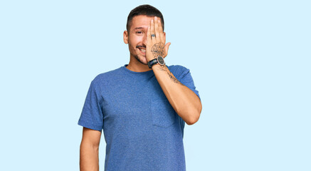 Sticker - Handsome man with tattoos wearing casual clothes covering one eye with hand, confident smile on face and surprise emotion.