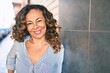 © Krakenimages.com - Middle age hispanic woman smiling happy leaning on the wall at the city.