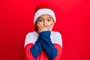 Canvas Print - Little boy hispanic kid wearing christmas hat shocked covering mouth with hands for mistake. secret concept.