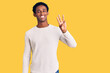 © Krakenimages.com - African handsome man wearing casual winter sweater showing and pointing up with fingers number three while smiling confident and happy.