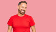 © Krakenimages.com - Handsome middle age man wearing casual red tshirt winking looking at the camera with sexy expression, cheerful and happy face.