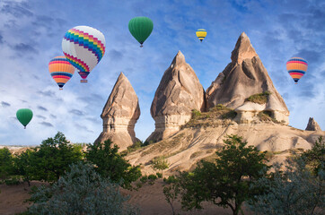 Wall Mural - Colorful hot air balloons flying over unique geological formations in Cappadocia, Central Anatolia, Turkey. Nevsehir, Goreme National Park.