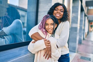 beautiful african american mother and daughter smiling happy and hugging. standing with smile on fac
