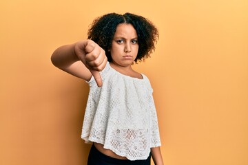 Sticker - Young little girl with afro hair wearing casual clothes looking unhappy and angry showing rejection and negative with thumbs down gesture. bad expression.