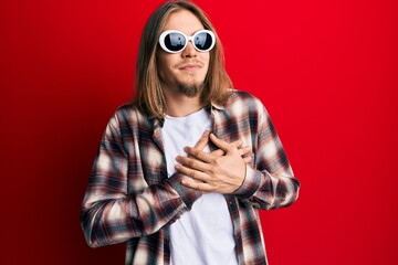 Sticker - Handsome caucasian man with long hair wearing hipster shirt wearing sunglasses smiling with hands on chest, eyes closed with grateful gesture on face. health concept.