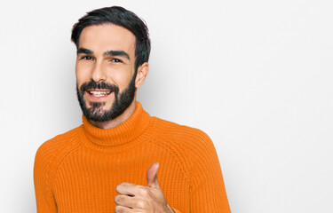 Young hispanic man wearing casual clothes doing happy thumbs up gesture with hand. approving expression looking at the camera showing success.