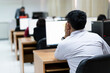 © EduLife Photos - Blur and selective focus of the adult university learners wearing a face mask while concentrating on doing online examination in the computer room. Serious students working on computer at university