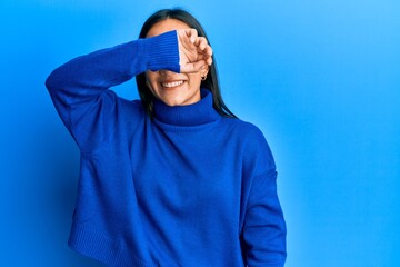 Poster - Young asian woman wearing casual winter sweater covering eyes with arm smiling cheerful and funny. blind concept.