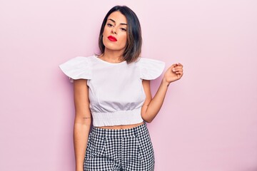 Wall Mural - Young beautiful brunette woman wearing casual clothes standing over isolated pink background