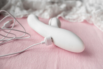 white silicone vibrator with vacuum mode on pink lace background with magnetic charging