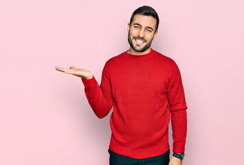 Young hispanic man wearing casual clothes smiling cheerful presenting and pointing with palm of hand looking at the camera.