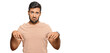 Handsome hispanic man wearing casual clothes pointing down looking sad and upset, indicating direction with fingers, unhappy and depressed.