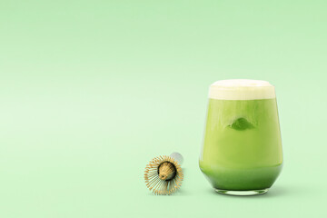 A glass of iced matcha latte on a green background with copy space.