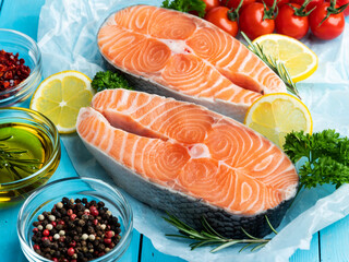 two raw fresh steak fish trout, salmon and spices on a blue wooden background, close up