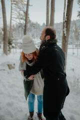 Canvas Print - Beautiful view of a couple wearing warm clothes, dancing and having fun at the snow park