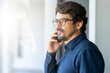 © Joao - Casual man wearing glasses talking on the phone. Successful male portrait at the office by the window