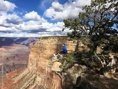 Man Sitting On Cliff At Grand Canyon National Park
