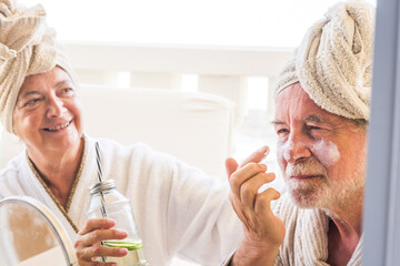 couple of two seniors or mature people taking a drink or cocktail together at home or in a hotel in a massage treatment