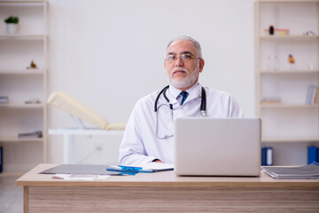 Old male doctor working in the clinic