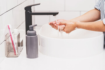 Closeup-up Asian woman hand washing with faucet water in Bathroom at home, Health care of Covid-19 pandemic , cleaning and carefree concept