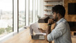 © fizkes - Concentrated young african man read printed document before laptop screen compare data think on text edit check errors. Thoughtful black male analyse financial report plan changes in contract project