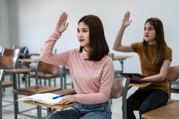 Young woman college students sitting on lecture chair in classroom studying, writing on examination paper answer sheet in doing the final examination test. College students in the classroom