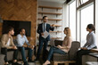 © fizkes - Enthusiastic male boss ceo team leader hand out set tasks to international workforce members on daily briefing conference. Young business coach talk to diverse trainees ask for opinions at workshop