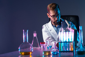 Poster - bearded chemist on the background of test tubes and a microscope. a man in a white coat is sitting i