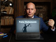 Man wearing blue business suit and showing laptop with written text False Statements . Blurred background. Horizontal mockup