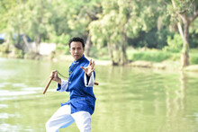 Portrait Of Man Exercising With Nunchaku By Lake