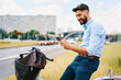 © baranq - Young man looking at smartphone while waiting on street crossing riding a city bike