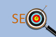 © vallerato - SEO. Search engine optimization. Illustration with a word, a magnifying glass, and a target with an arrow hitting the target. Isolated on a light blue background. Design element.