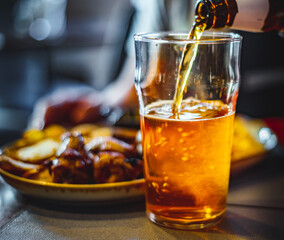 Wall Mural - pouring beer in glass from bottle on bar or pub