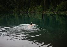 A Young Woman Swimming In A Lake On A Smoky Evening 
