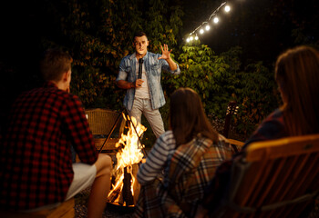 Wall Mural - friends tell scary stories by the bonfire, camping