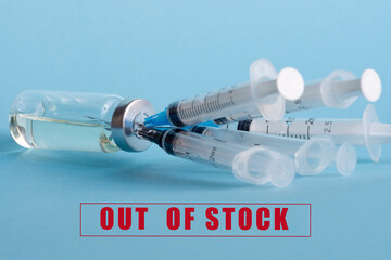 An ampoule with medicine and five syringes stuck in the bottle cap, on the background of the inscription: out of stock. The concept of a shortage of influenza and coronavirus vaccines