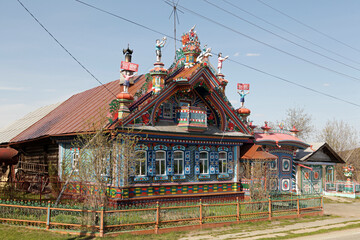 Smith Kirillov's wooden house with carved windows, frames in Kunara village, Sverdlovsk region, Russia. Traditional russian folk style in architecture, Lenin's portrait and Soviet symbolics. Naive art