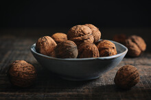 Walnuts In A Blue Grey Dish On A Dark Background. Dark Moody Minimalism Food Photography Style. Horizontal Still Life With Copy Space.