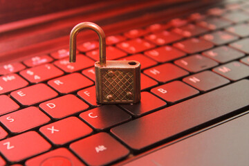 Open padlock on computer keyboard, red glow, symbol of hacked security